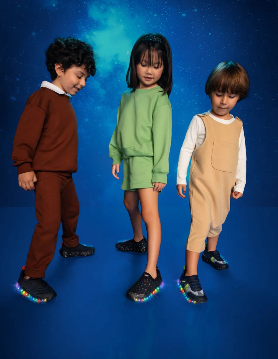 Three kids looking down at their light-up trainers